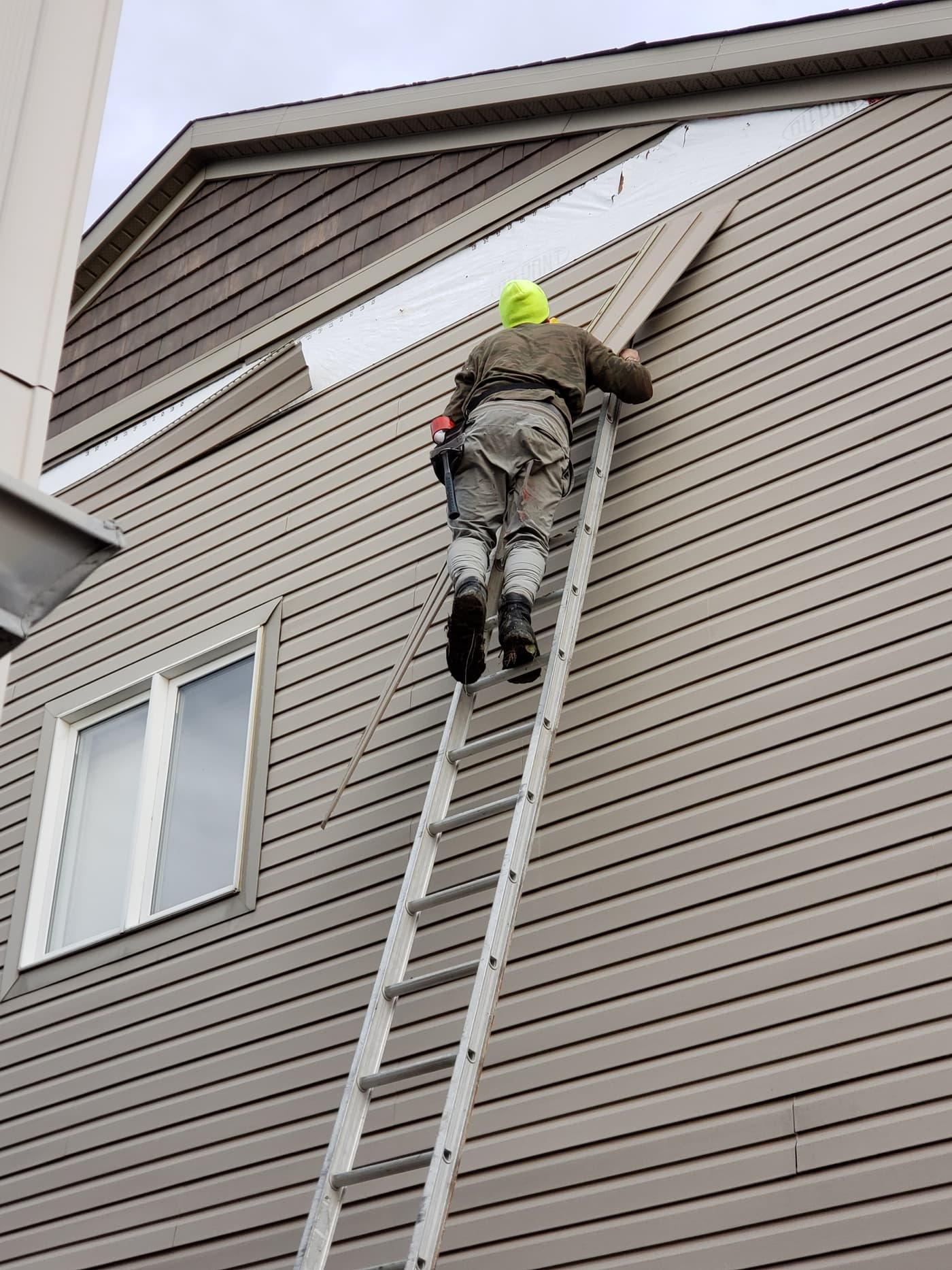 Exterior remodeling contractors on a ladder repairing siding on a home